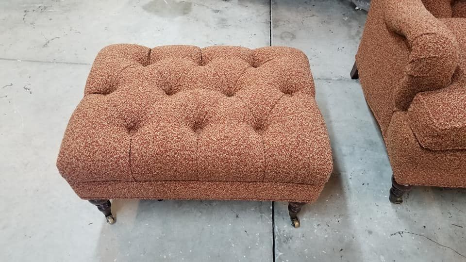 Tufted orange patterned ottoman with wooden legs, next to a matching chair.