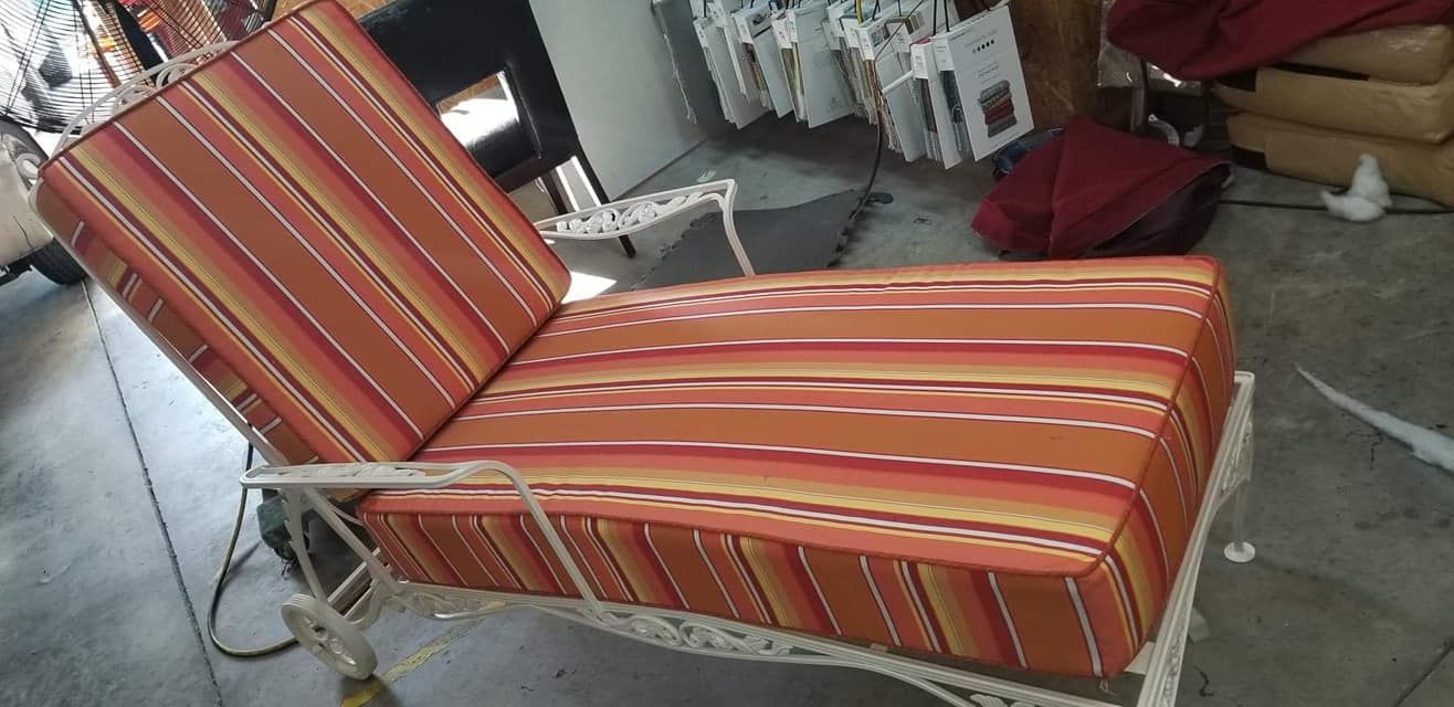 A white wicker chaise lounge with orange striped cushions.