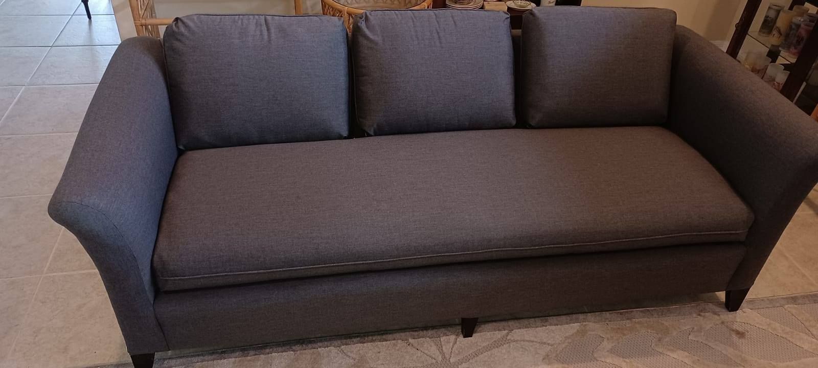 Gray sofa with three back cushions, in a room with tile floor.