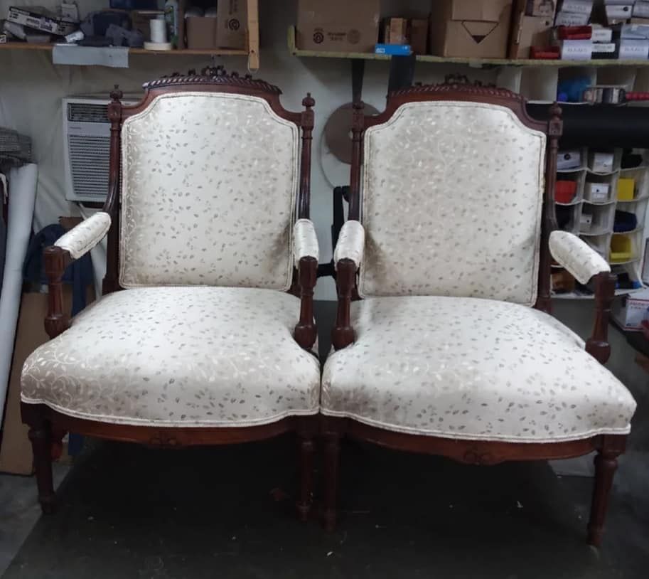 Two antique armchairs with cream patterned upholstery and dark wood frames, indoors.