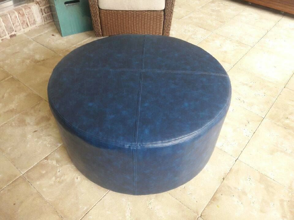 Blue round ottoman on a tiled patio, near a wicker chair.