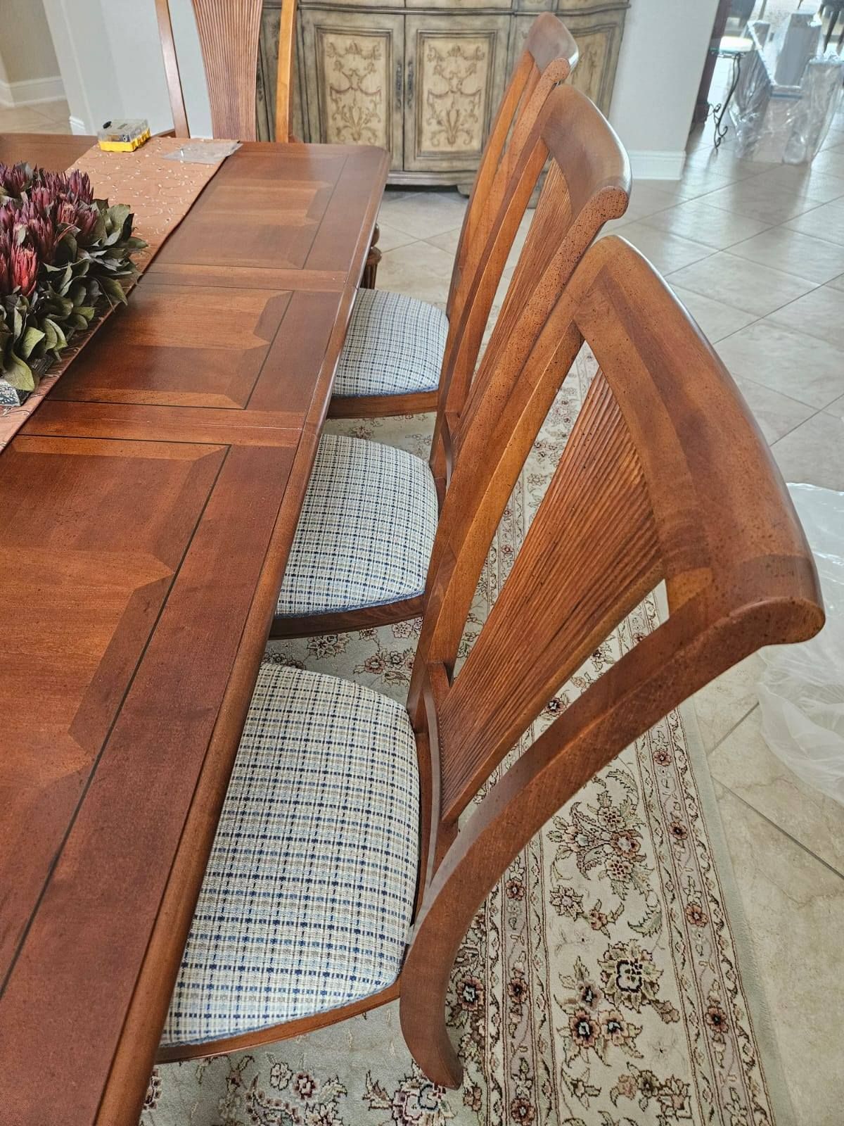 Wooden dining table with several matching chairs. The chairs have curved backs and patterned seat cushions.