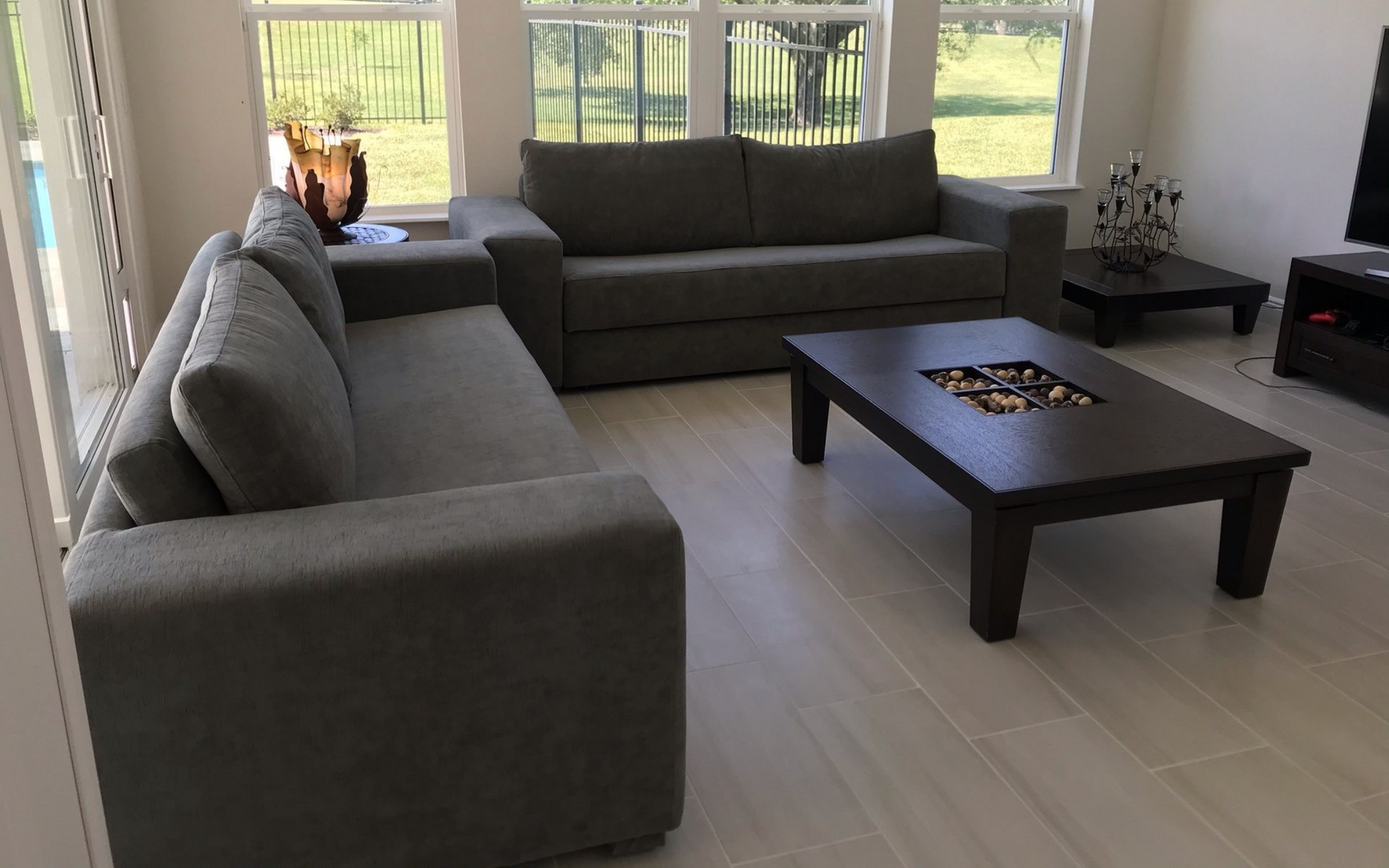 Living room with gray sofas, dark coffee table, and windows overlooking a grassy yard.