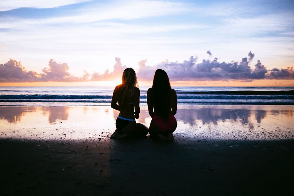 Two girls on the beach looking at the sunset