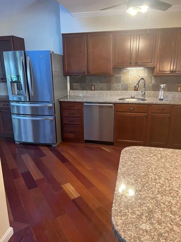 Modern kitchen with wood cabinets, stainless steel appliances, granite counters, and hardwood floors