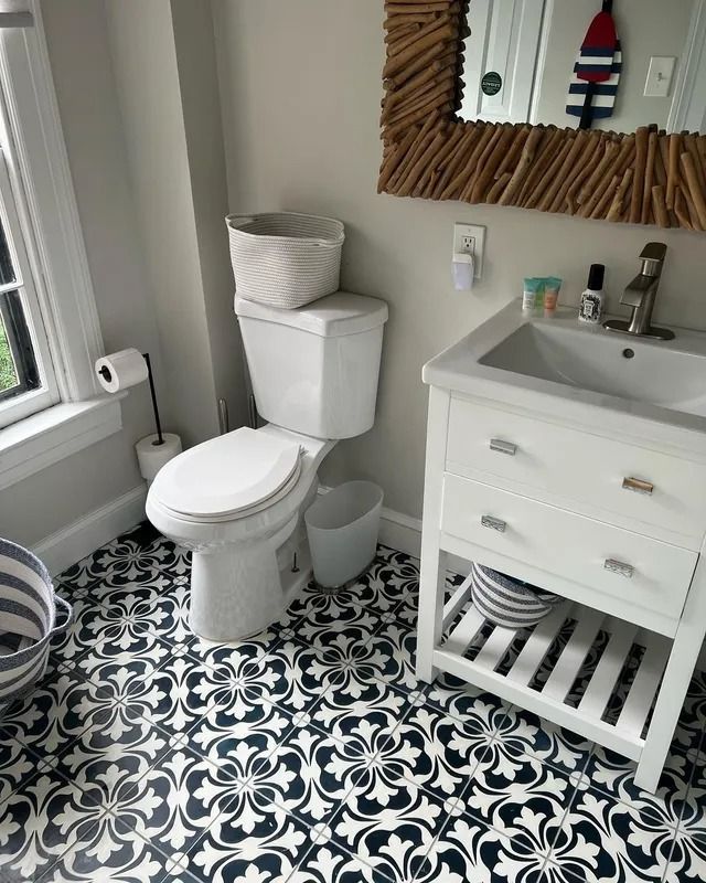 Small bathroom with black-and-white patterned tile, white toilet and sink vanity, and a window by the tub.