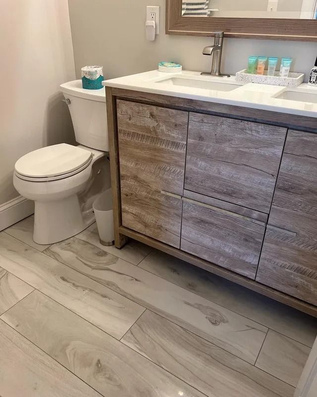 Bathroom vanity and toilet with light wood flooring and wood cabinet drawers under a sink