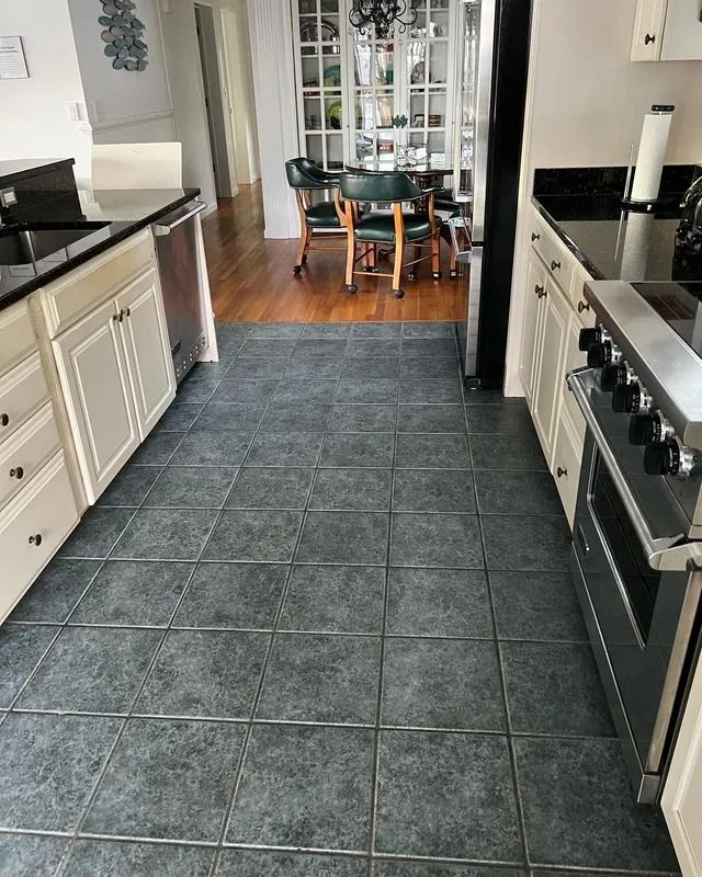 Modern kitchen with dark tile floor and black-and-white cabinets leading to a dining area