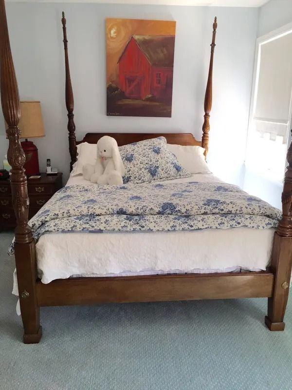 Four-poster bed with blue floral bedding and a white stuffed dog in a bright bedroom