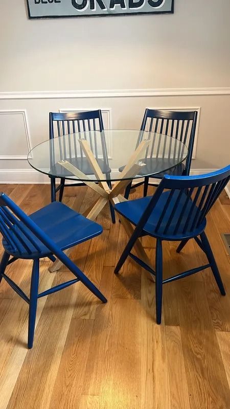 Blue chairs around a glass round table on a wooden floor in a bright room
