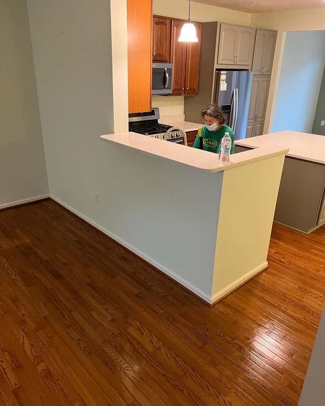 Person working at a kitchen pass-through counter in a bright home with hardwood floors
