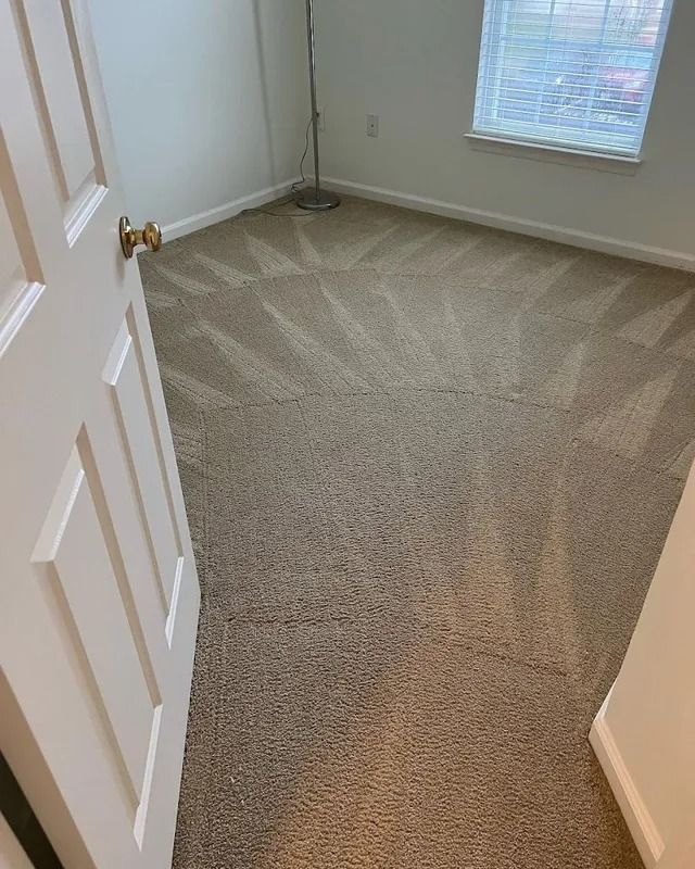 Empty carpeted room with beige walls, white trim, and a window letting in daylight