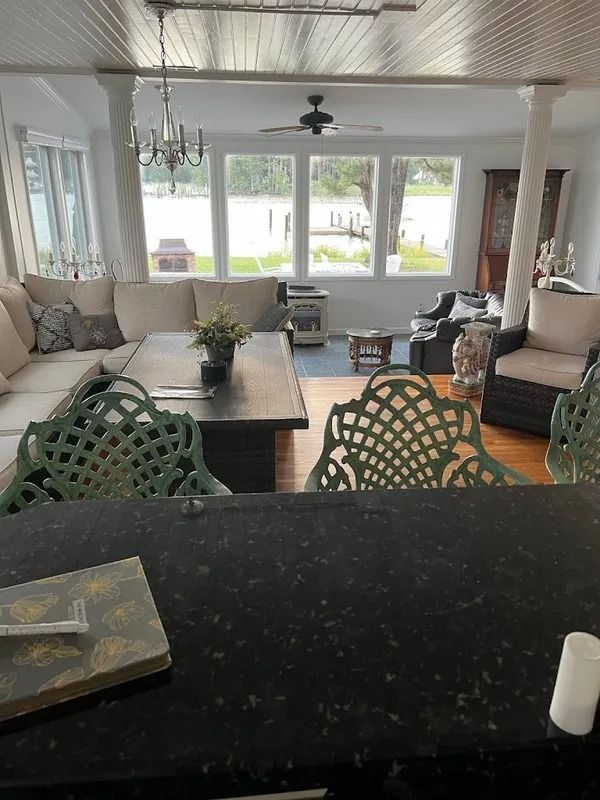 Bright living room with large windows, sofa, dining table, and black kitchen counter in foreground.
