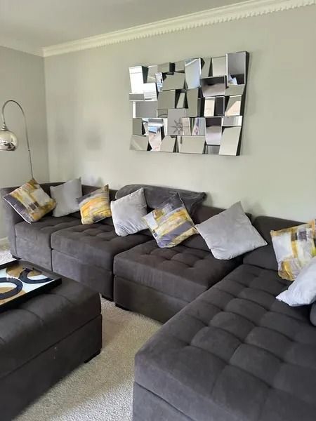 Modern gray living room with tufted sectional sofas, patterned cushions, and geometric wall art