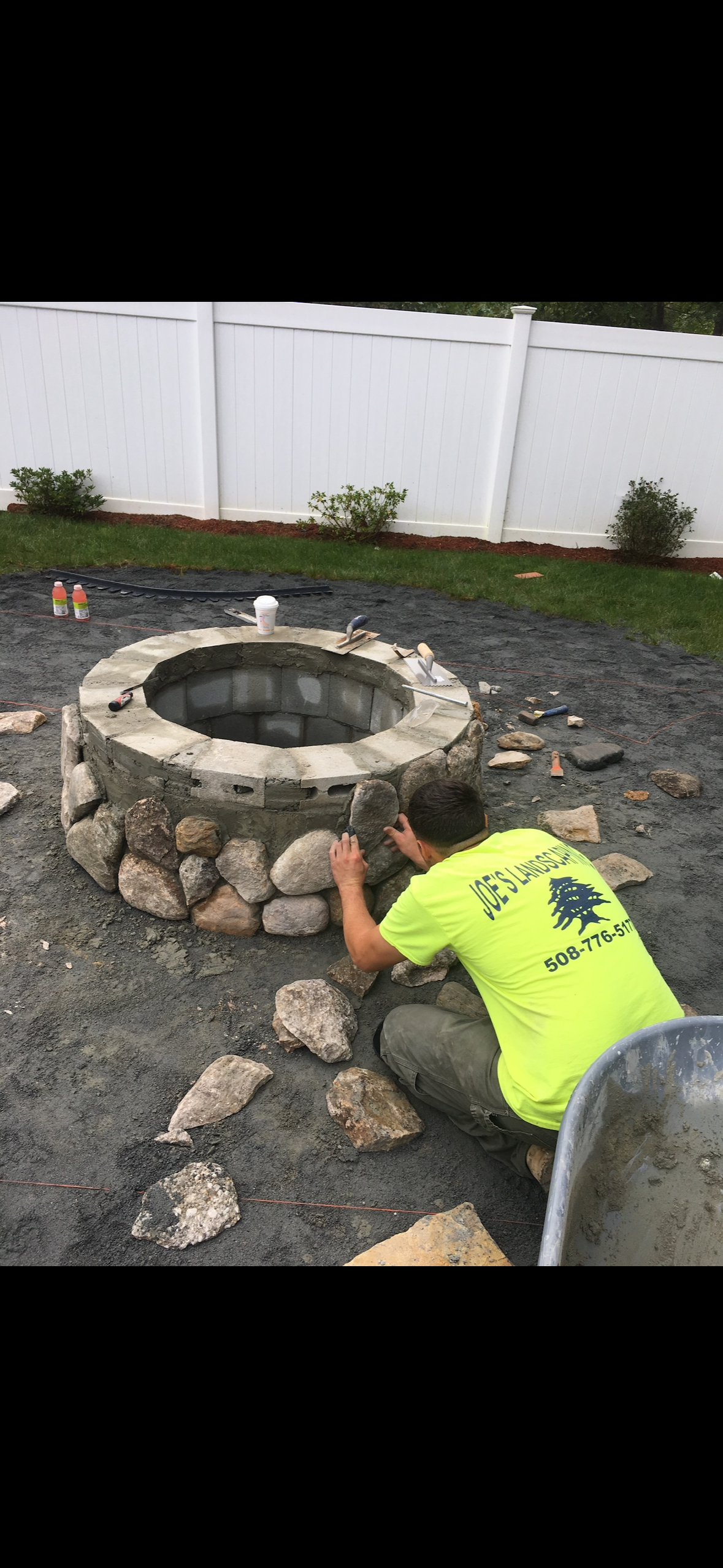 A man is kneeling down in front of a fire pit.