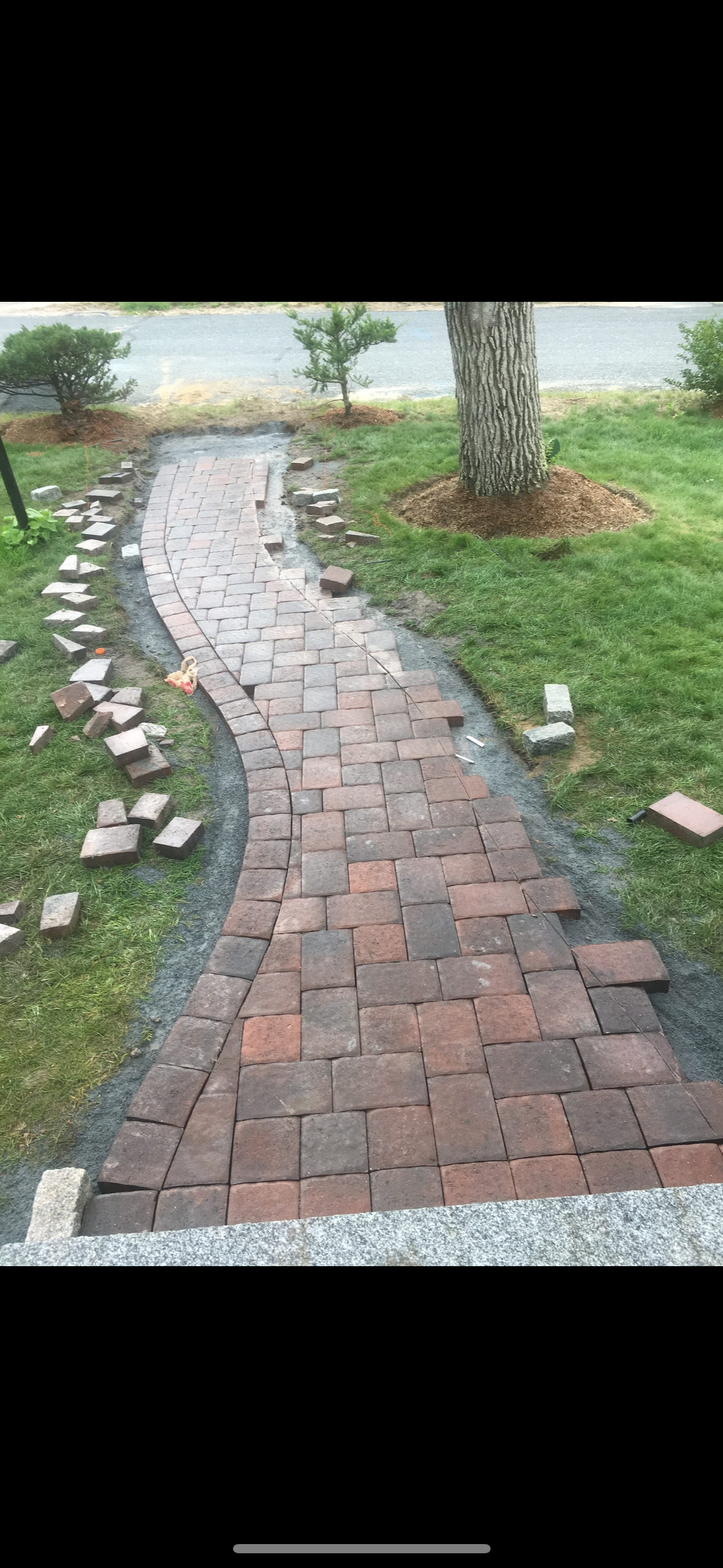A brick walkway is being built in a yard.