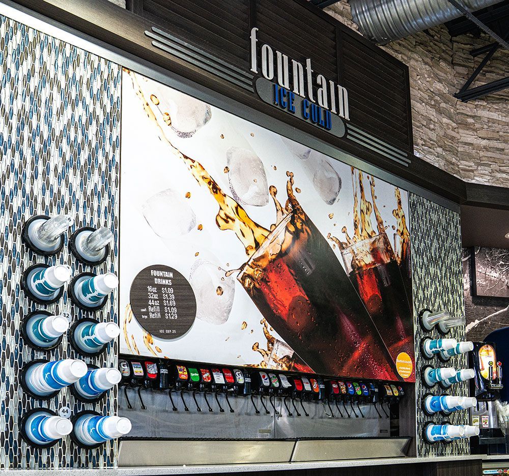Soda fountain with multiple drink dispensers, large advertisement, and ice.