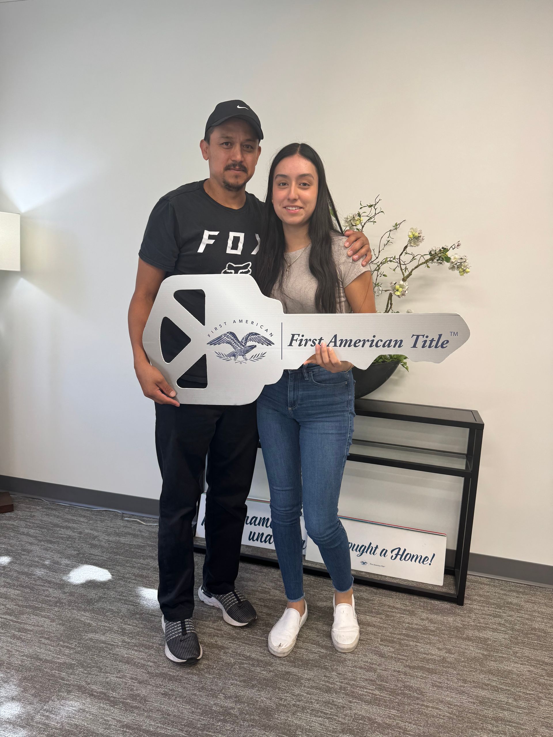 A man and a woman are standing next to each other holding a large key.