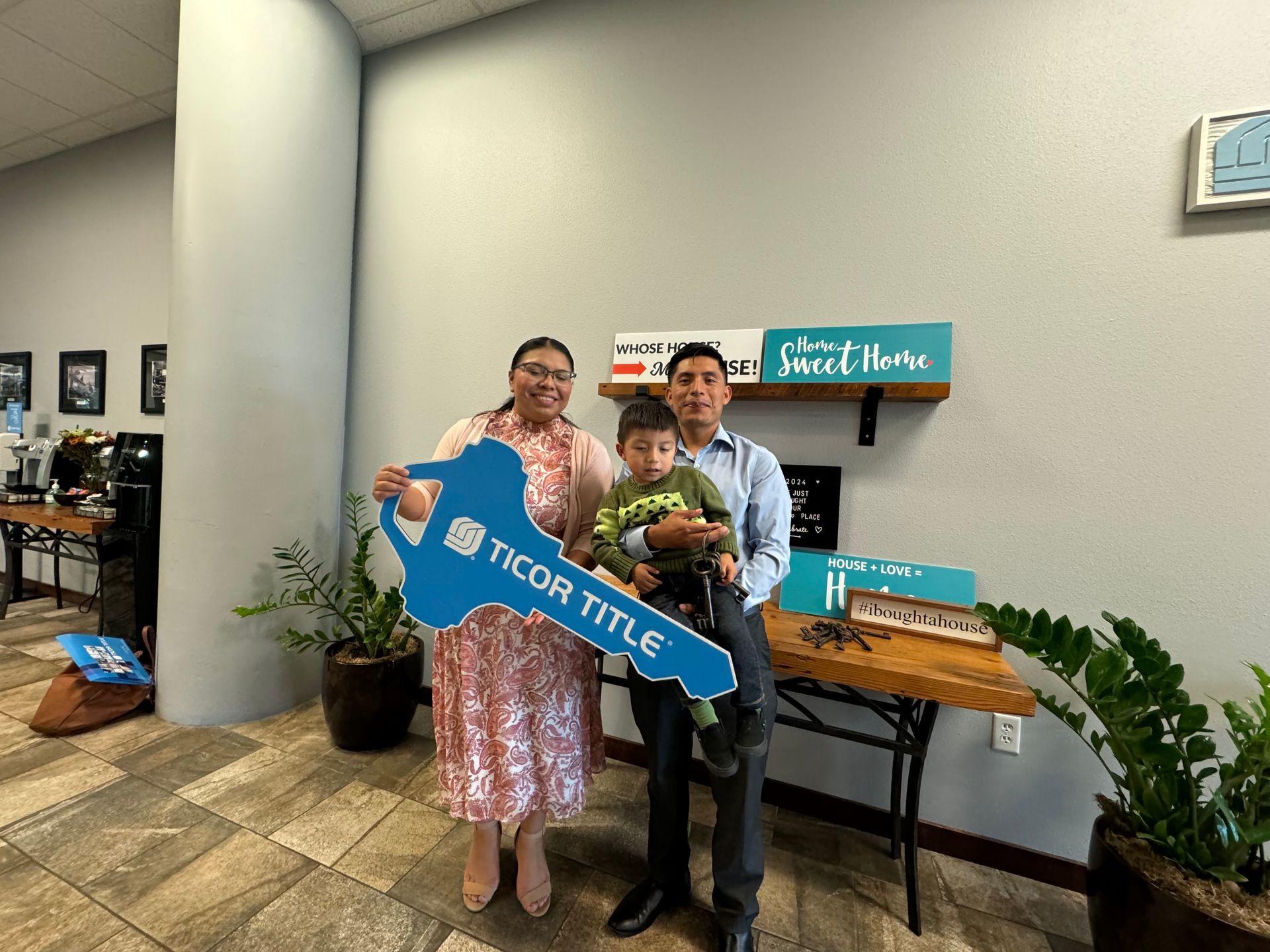 A family is holding a large key in a room.