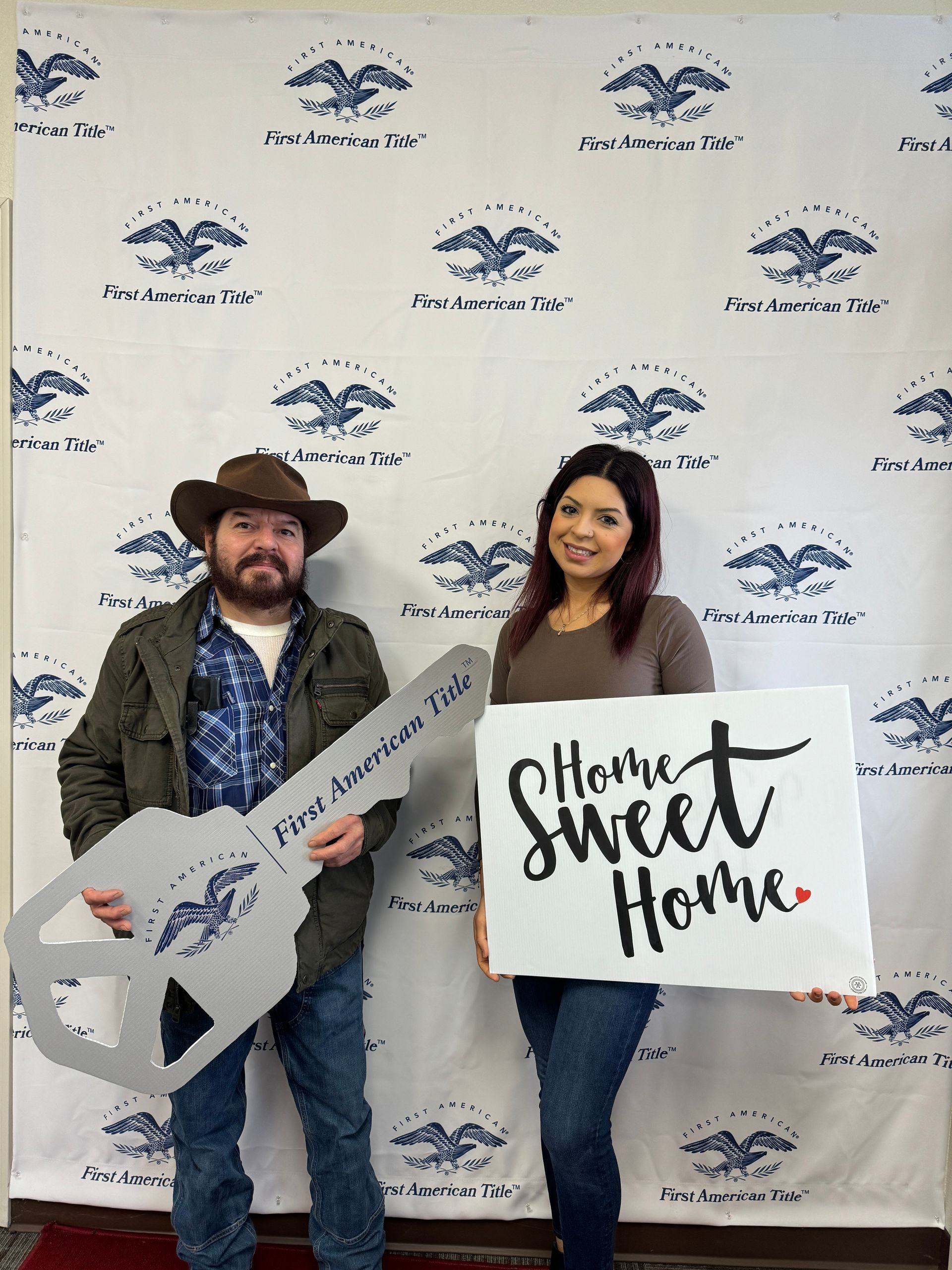 A man and a woman are holding a sign that says home sweet home.