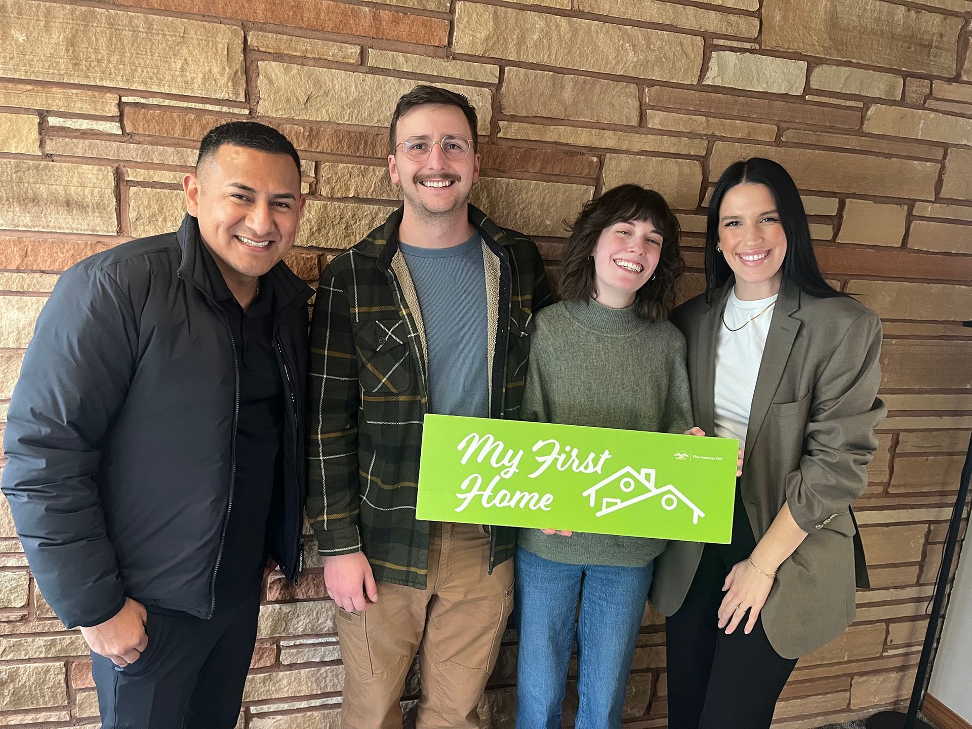 A group of people standing next to each other holding a sign that says `` my first home ''.