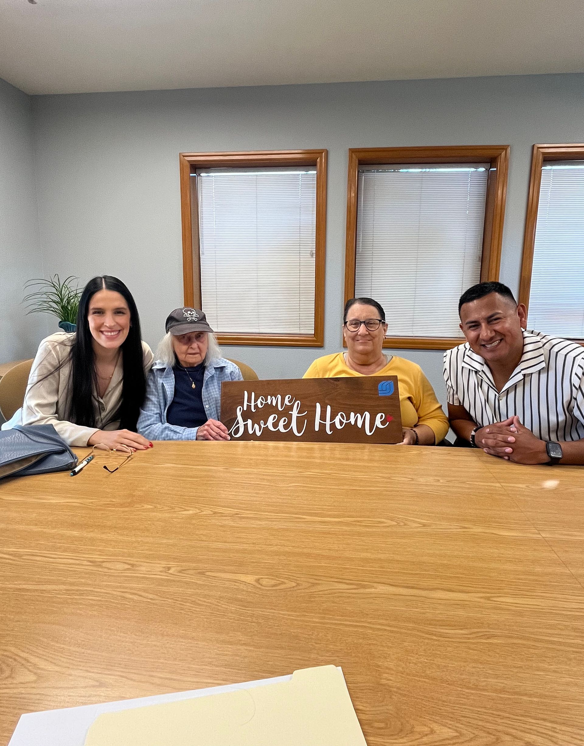 A group of people are sitting at a table with a sign that says `` home sweet home ''.