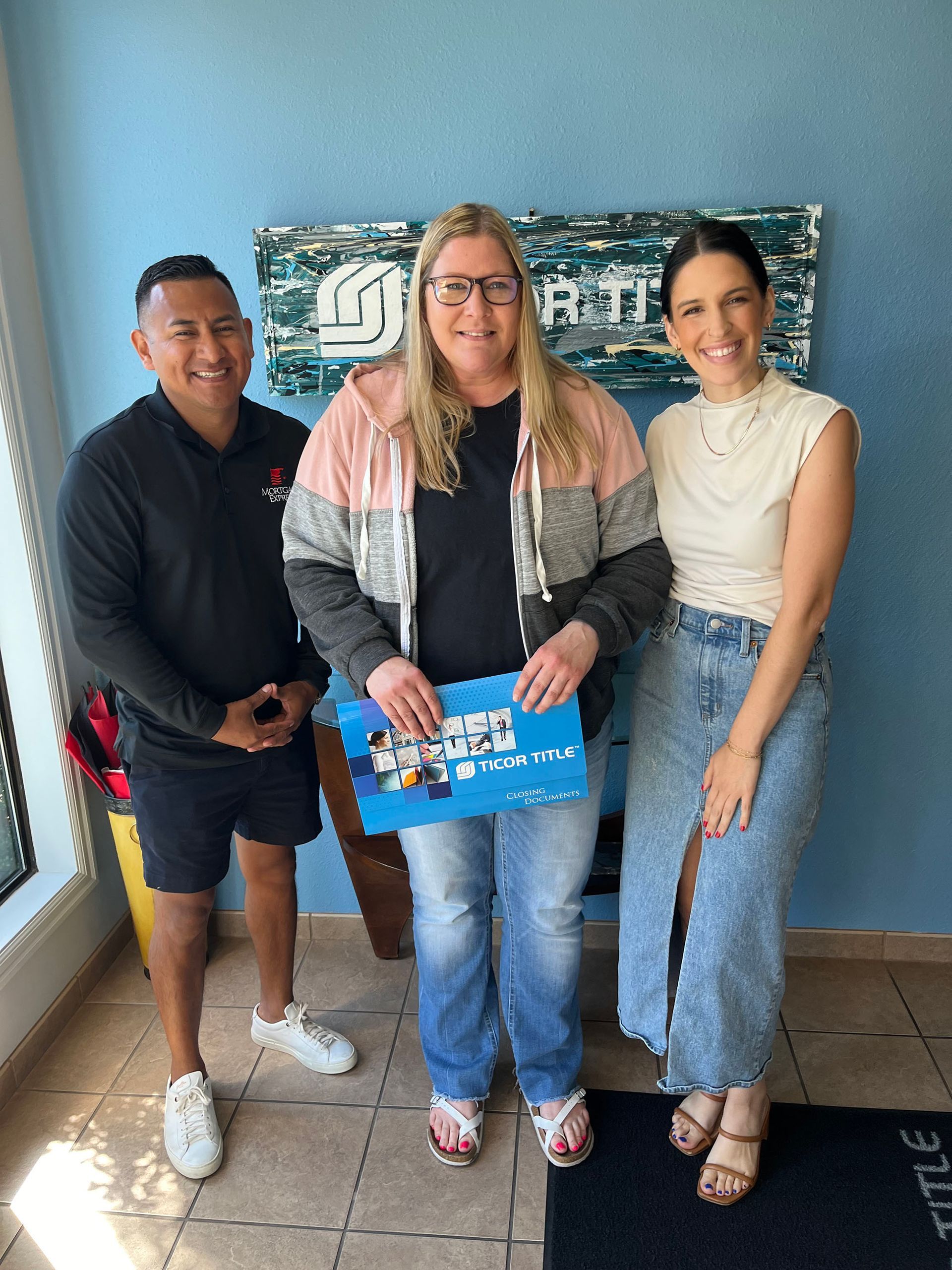 A man and two women are standing next to each other in a room.