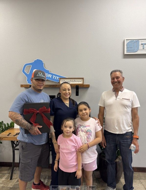 A family is standing in front of a house holding keys.