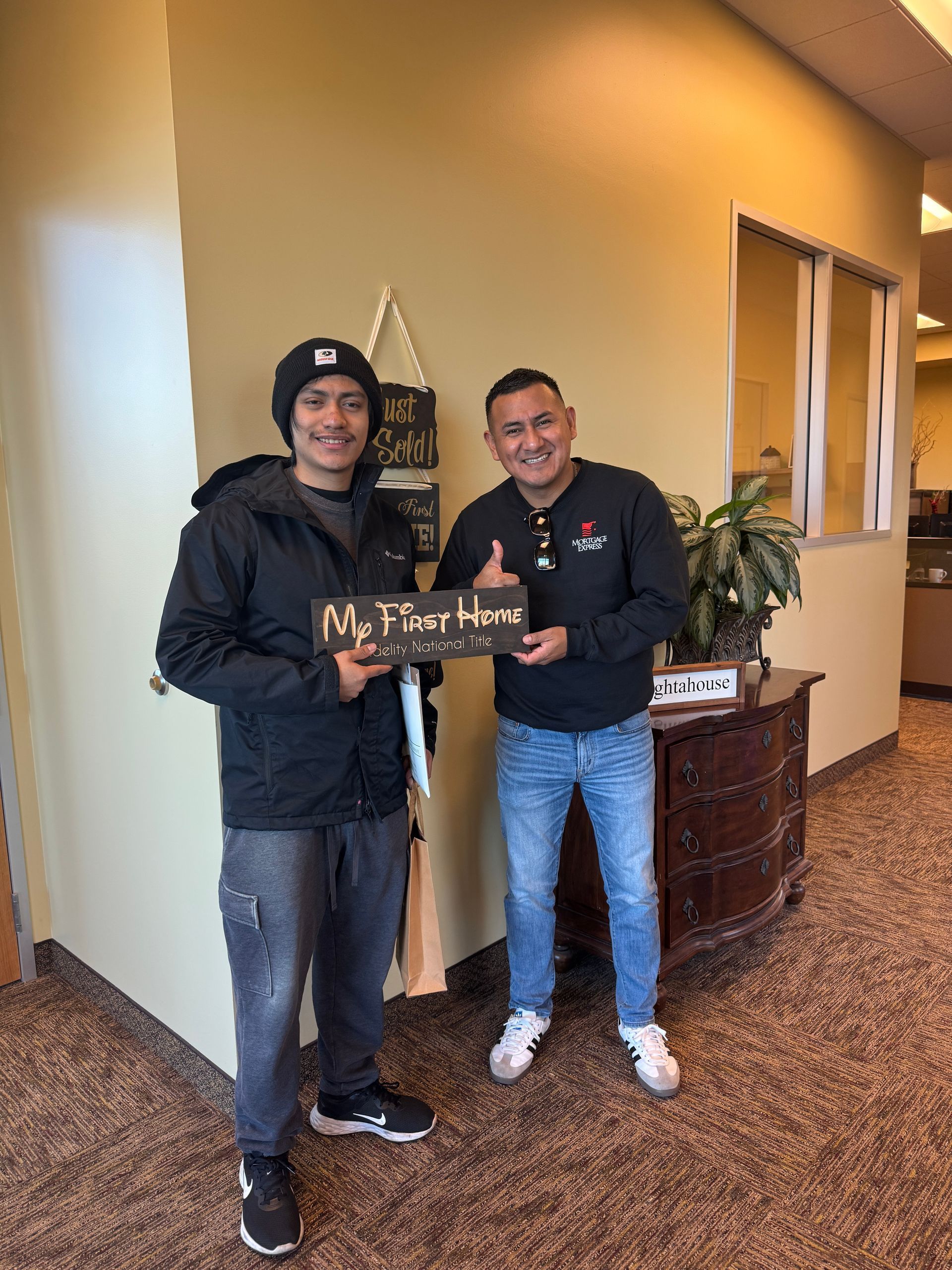 Two men are standing next to each other in a hallway holding signs