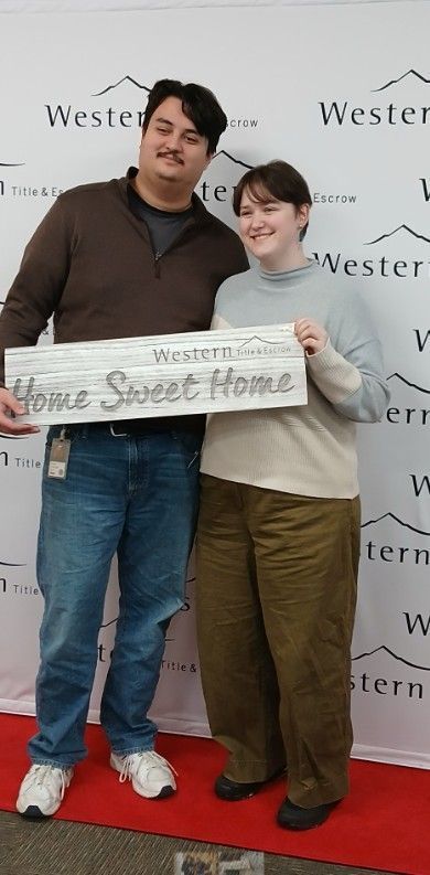 A man and woman holding a sign that says home sweet home
