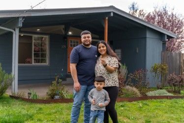 A family is standing in front of their new house.