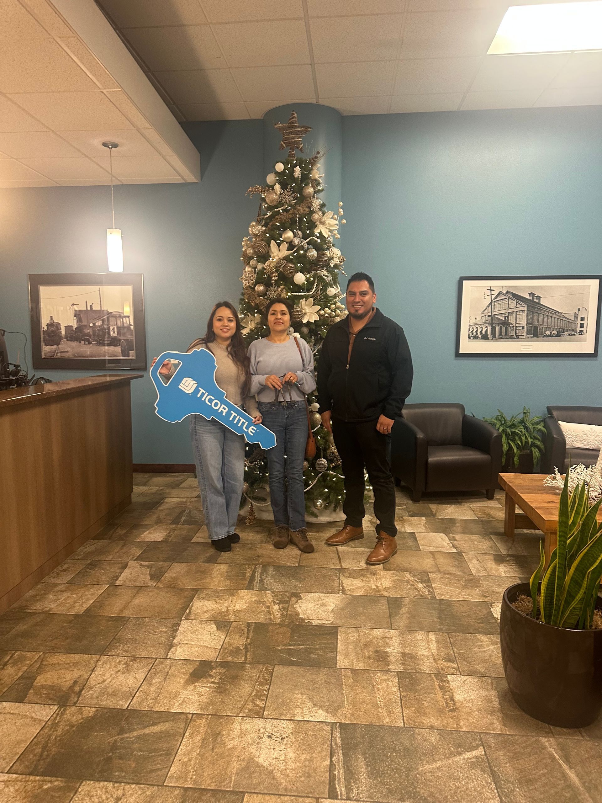A group of people standing in front of a christmas tree holding a key.
