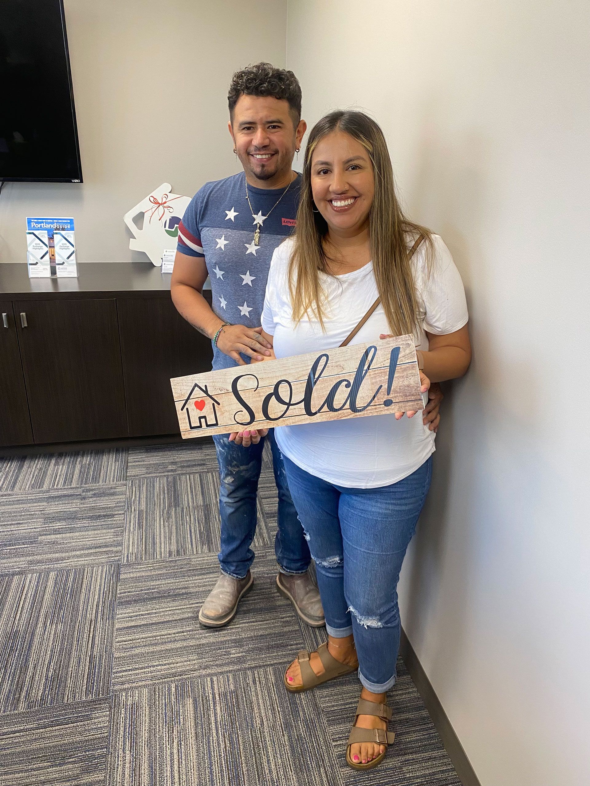 A couple holding a sold sign