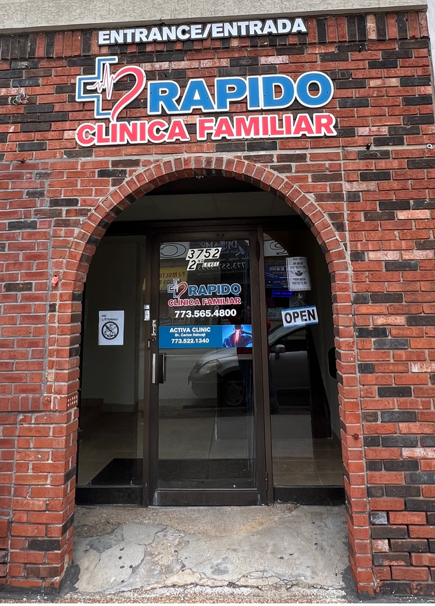 Medical receptionist and patient at a desk. Woman in scrubs takes patient's card; child waits nearby.