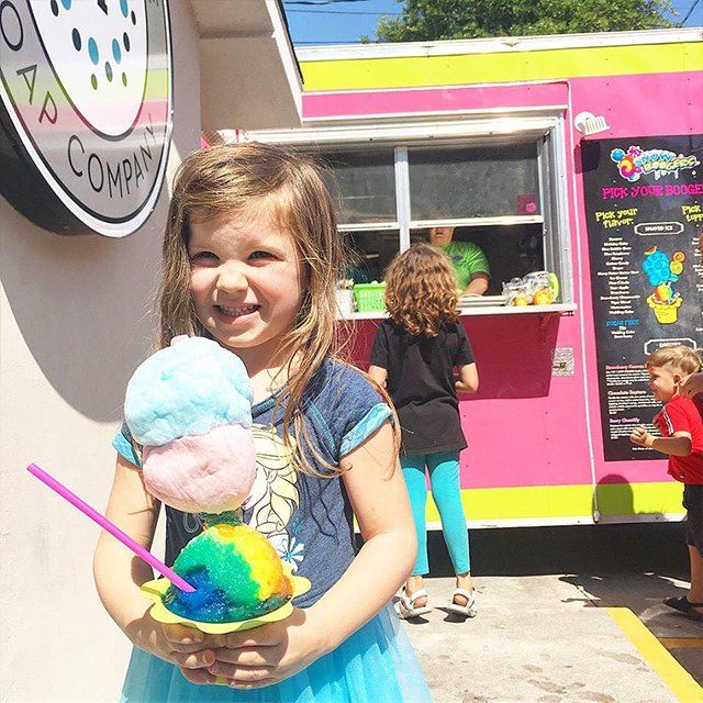 A little girl holding a cup of ice cream with a straw