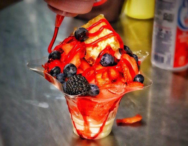 A cup of ice cream with strawberries and blueberries on top