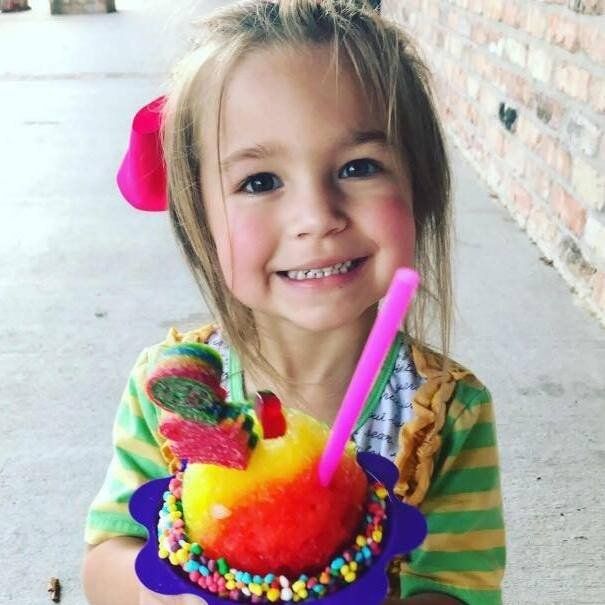A little girl holding a cup of ice cream with a pink straw