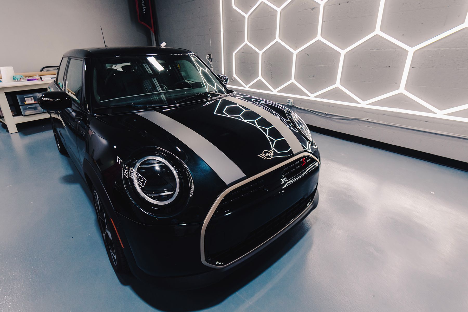 Two people tinting car windows in a shop. One holds a heat gun, the other works on the car door.