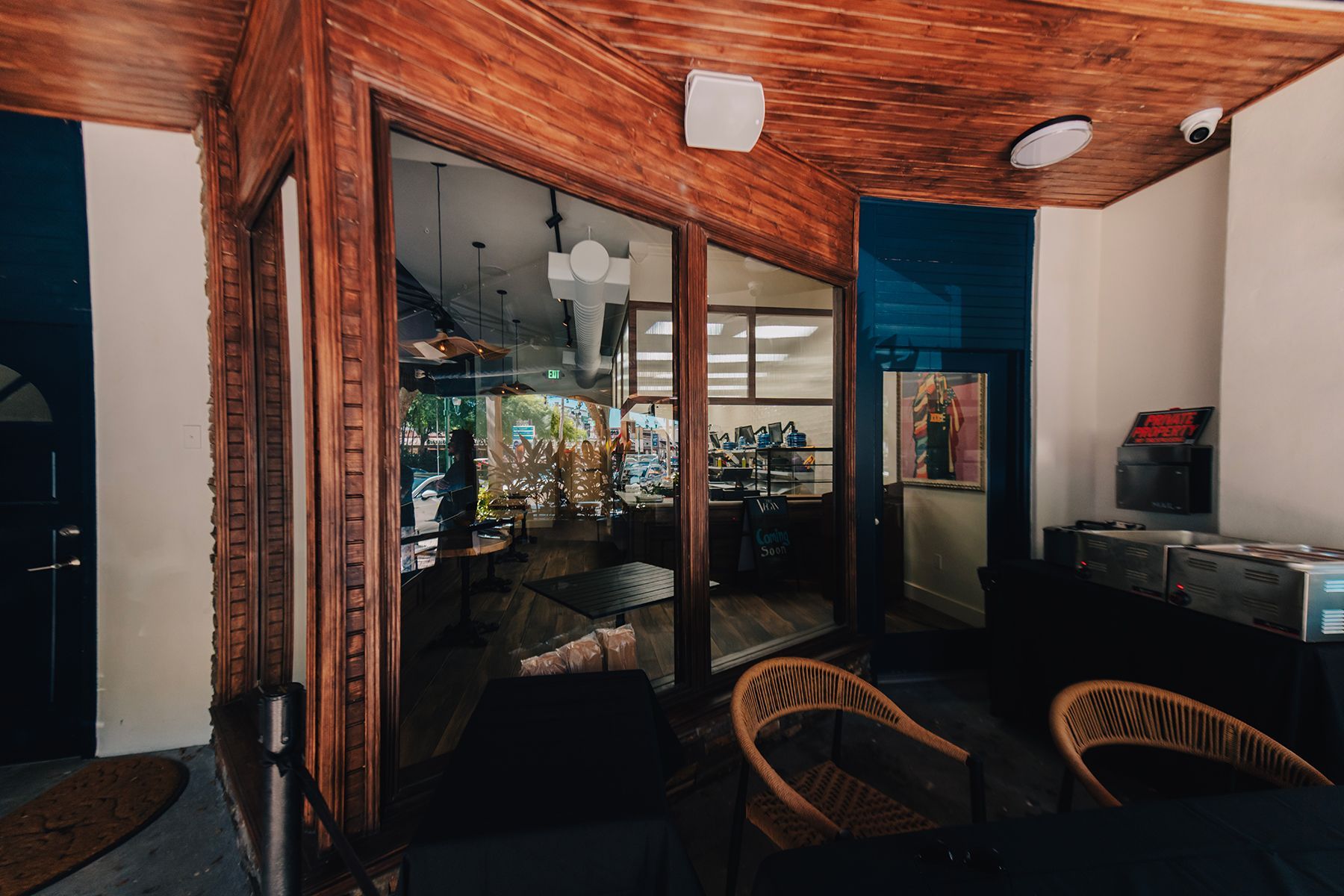 A cafe interior with wood trim, glass windows, seating, and a view of the counter and tables.