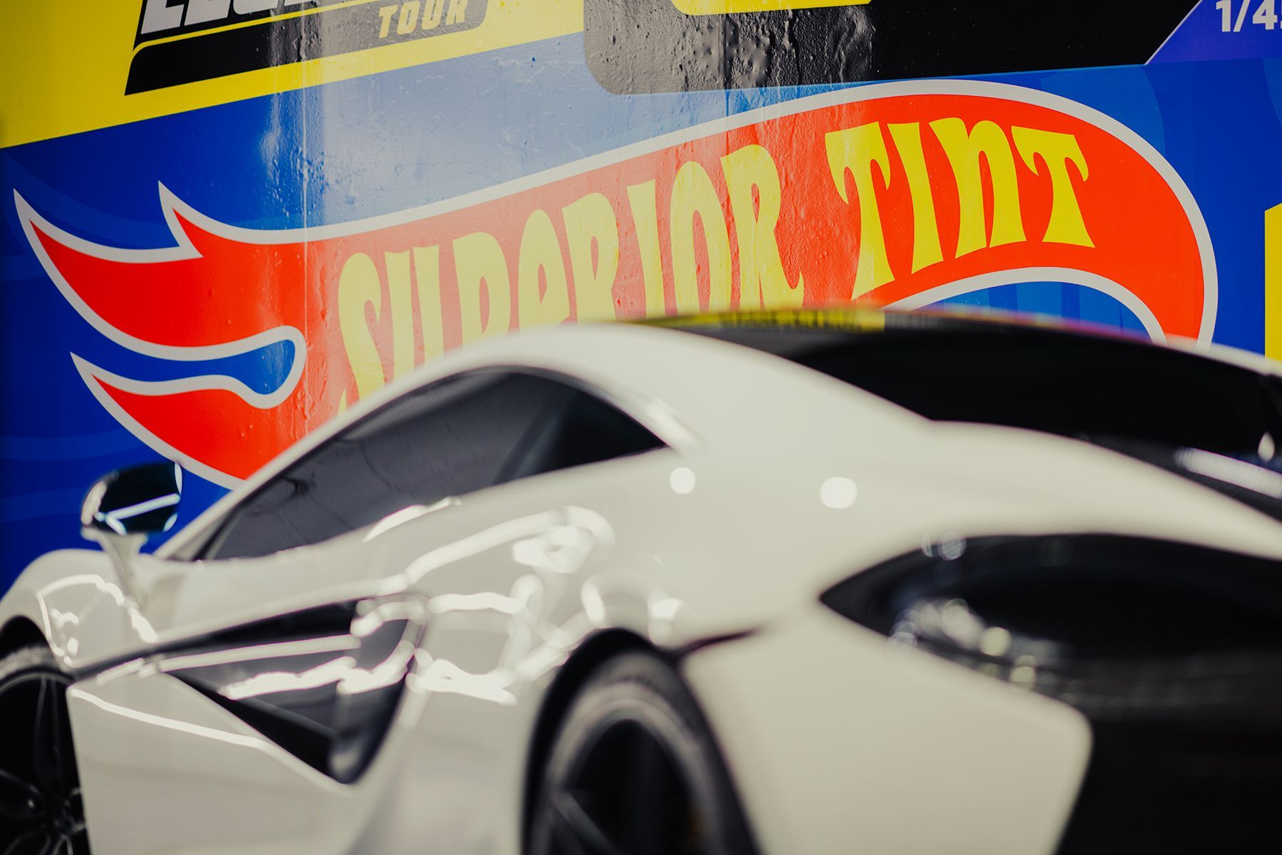 White toy sports car in front of a blue Hot Wheels package with 