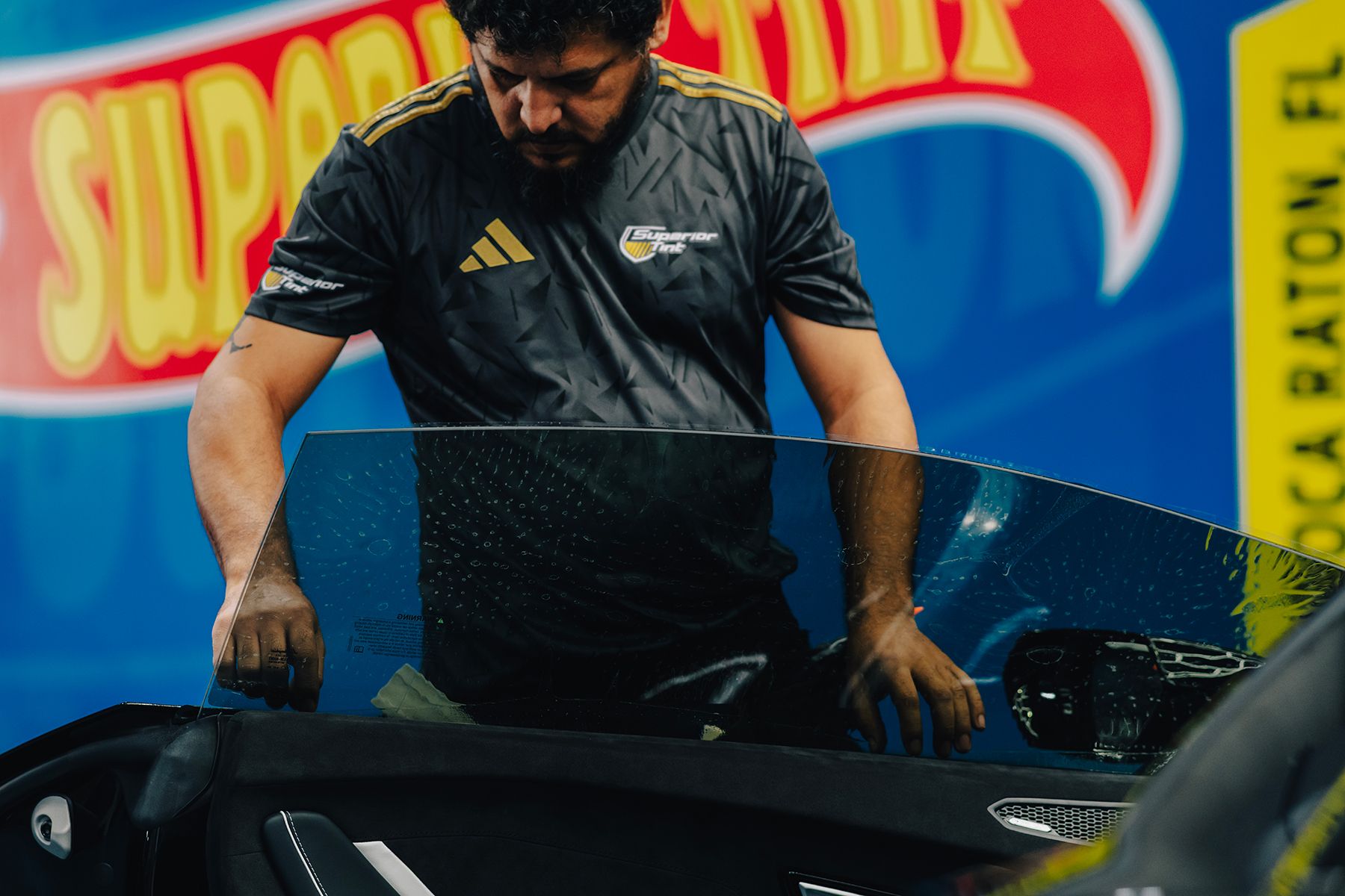 Man applying window tint to a car window, Boca Raton, FL.