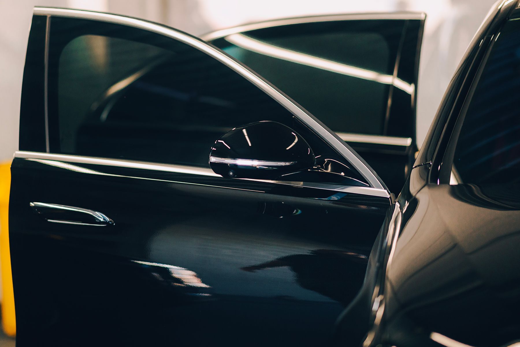 Black car with open doors, partially revealing the interior. The side mirror is visible.
