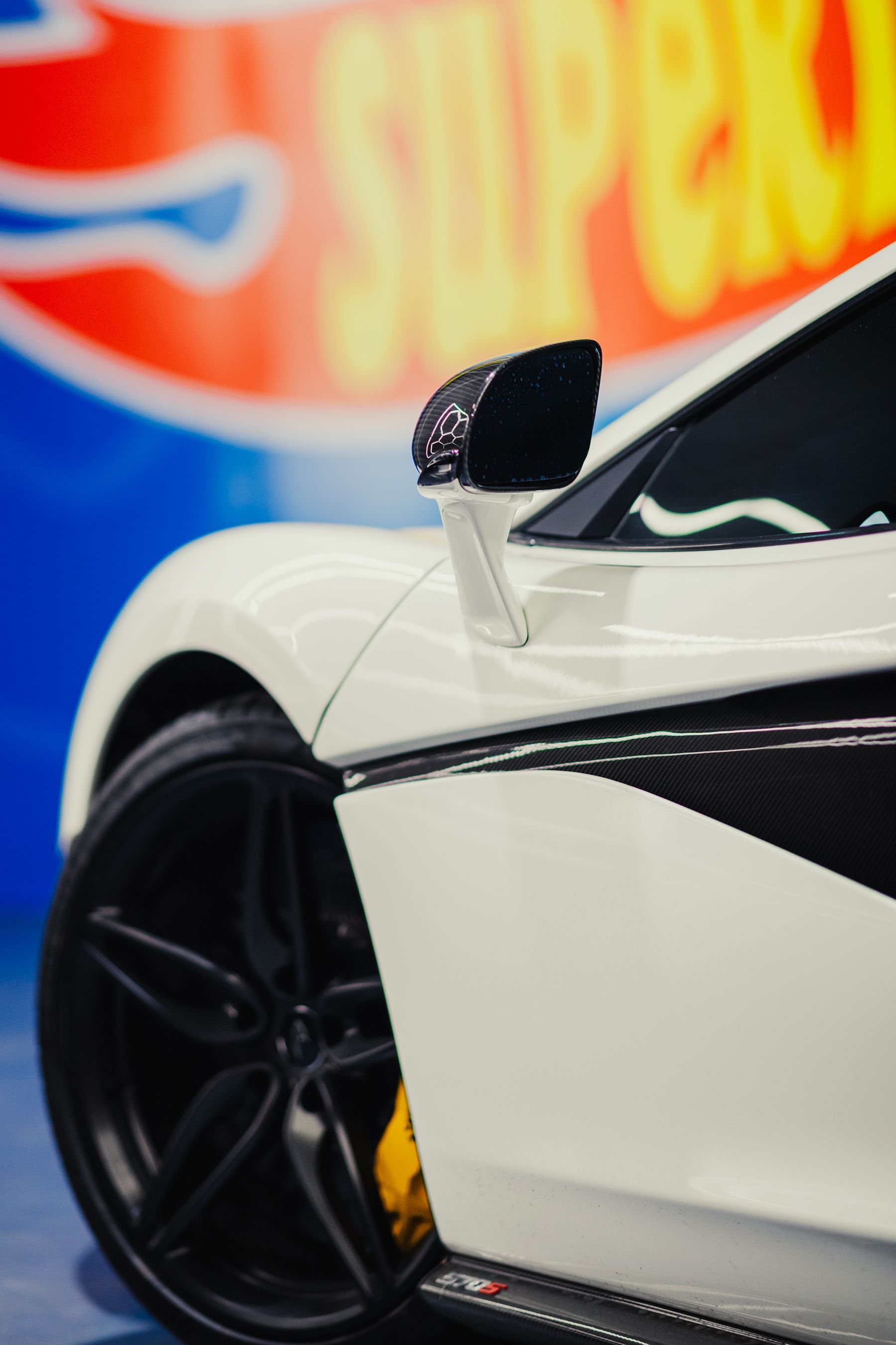 White sports car with black accents and wheel, yellow brake caliper.