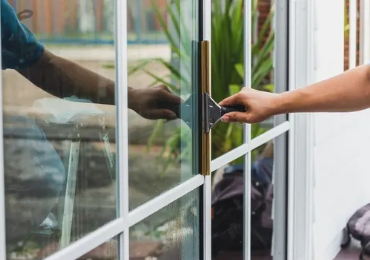 Person using a squeegee to clean a window.