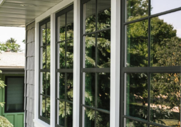 Close-up of four windows with black grids, surrounded by white trim and a shingled wall.
