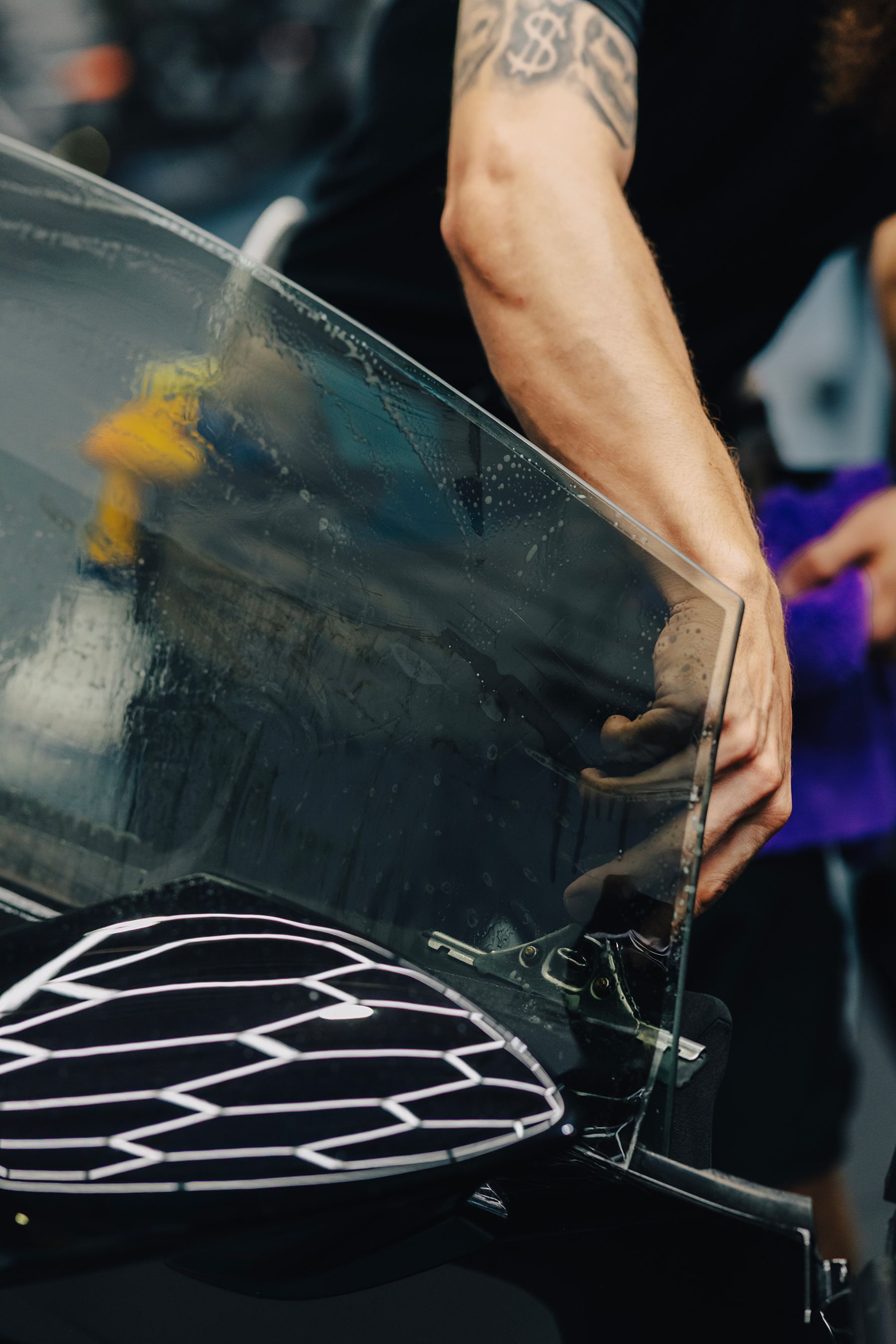 Person applying window tint to a car window; hands holding and positioning the film.