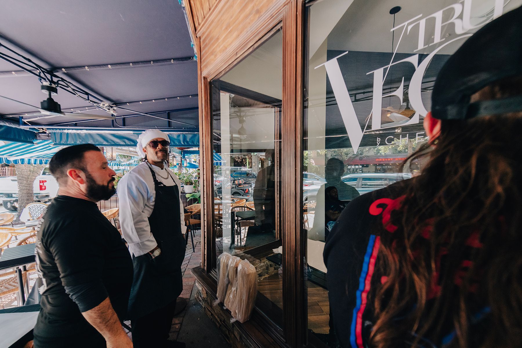 Three people looking into a storefront window. The sign reads 