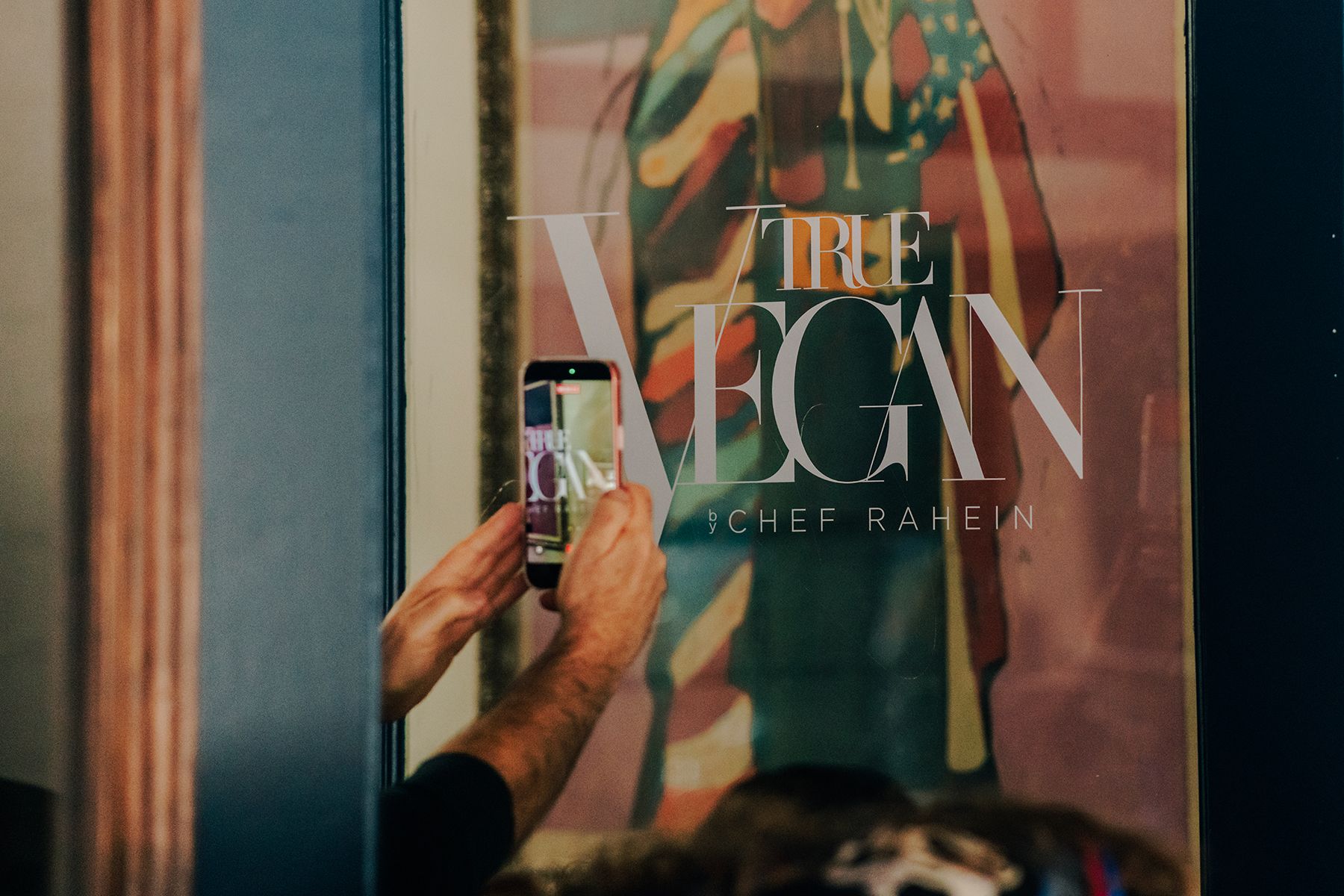 Person taking a photo with a phone of a framed poster with the words 