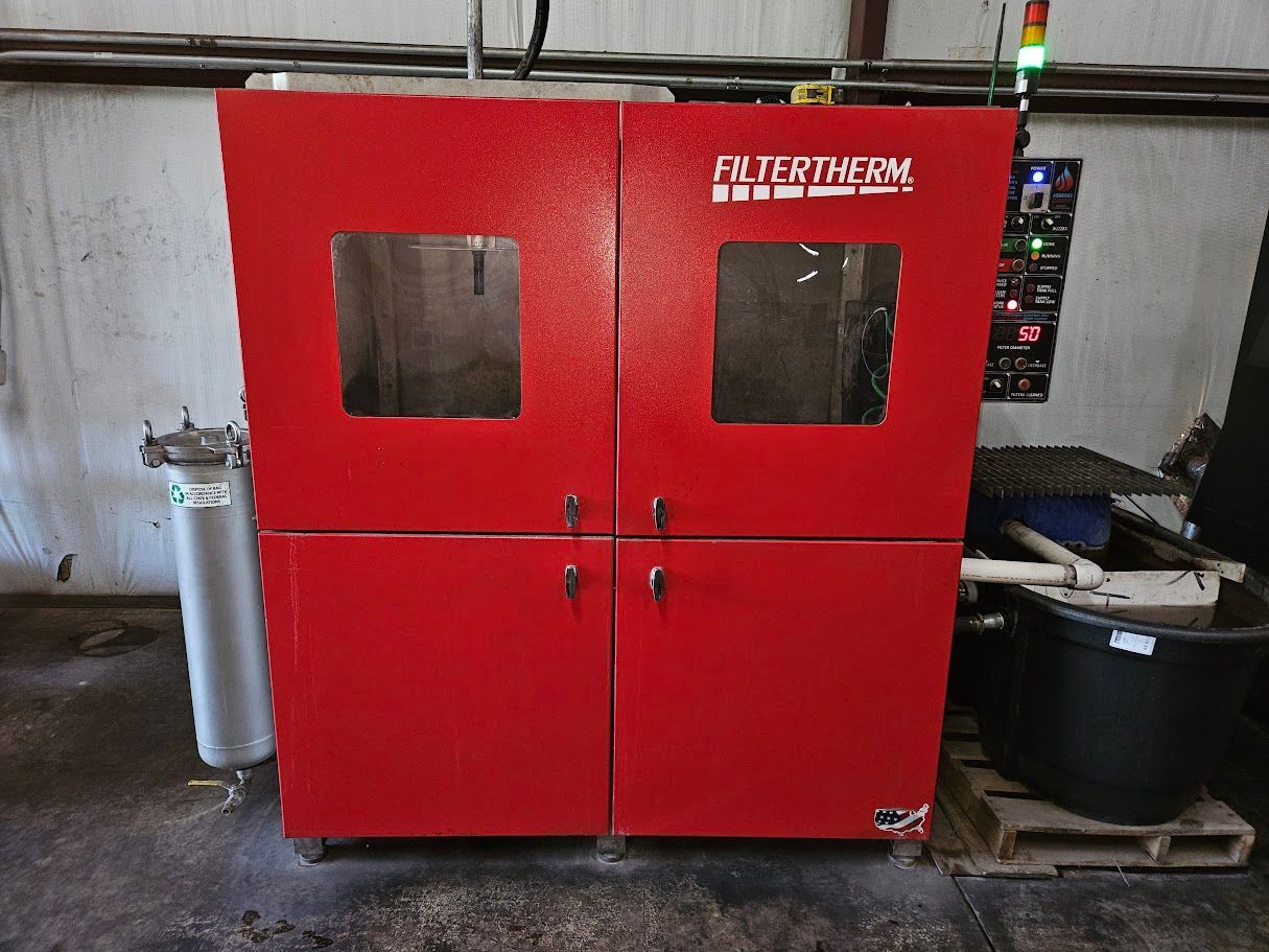 A bright red Filtertherm equipment cabinet with two windows and double doors sits in an industrial workshop.