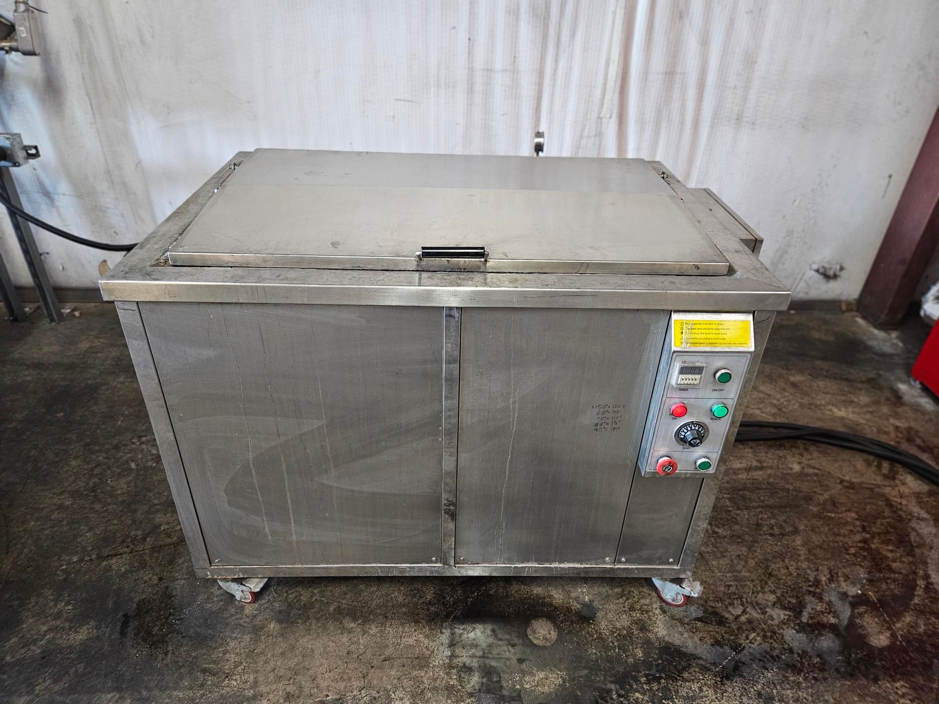 Stainless steel industrial washing or heating tank on wheels, featuring a control panel with buttons and a gauge.